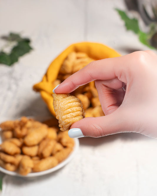 Hand holding cravve kalkal with a plate full of kalkal in the background