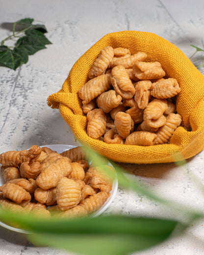 Yellow fabric basket filled with pasta looklikw but kalkal on a light surface.